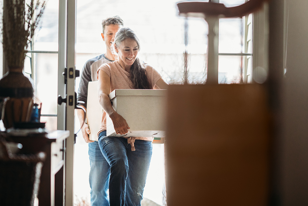 mature couple moving boxes through the back door of their home