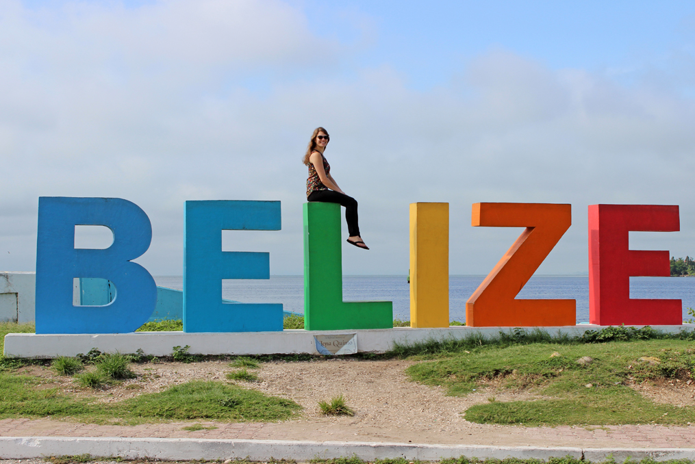 monica almroth sitting on the Belize sign at the beach