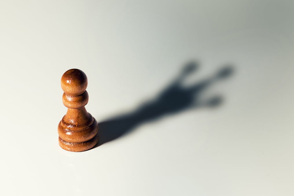 pawn casting the shadow of a king chess piece