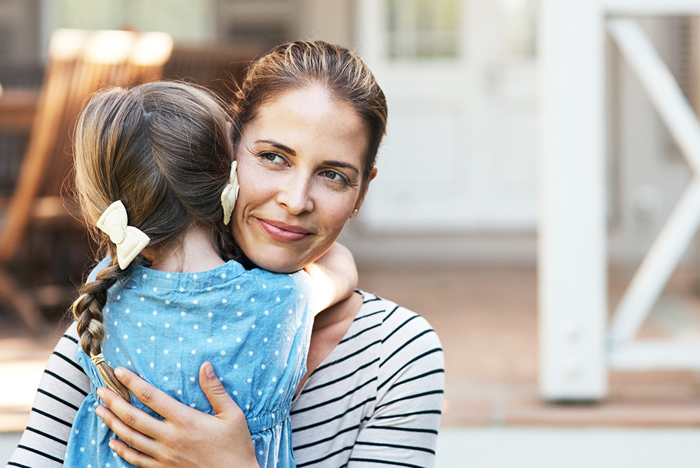 single mom giving her daughter a hug with a thoughtful look on her face