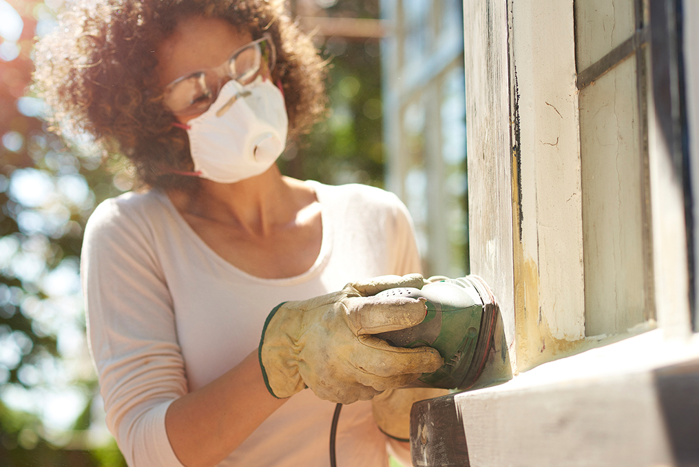 woman sanding a window frame on the outside of her new home making some home improvements