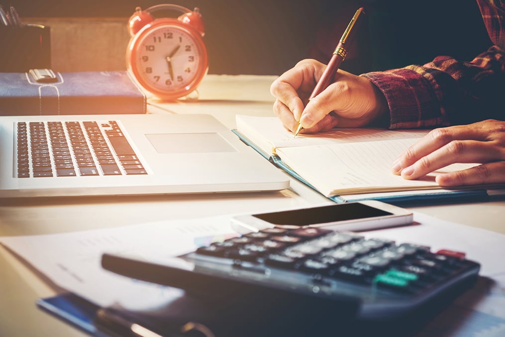 writing in a notebook on a cluttered desk