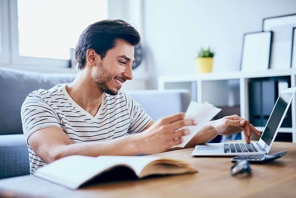 young man using his laptop to pay a bill online