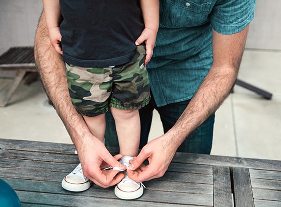 father helping son tie his shoes