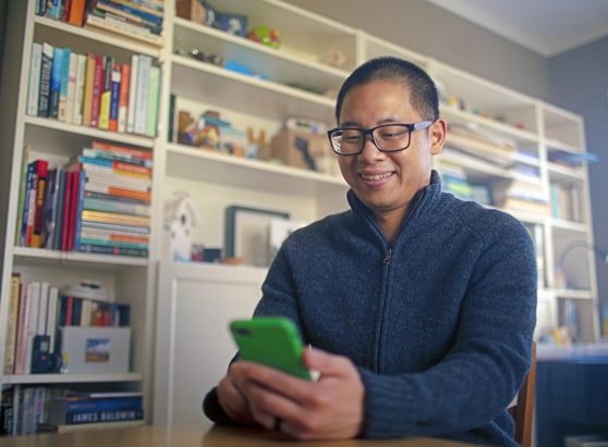 middle aged man sitting in his home office using mobile phone