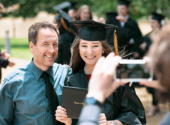 man and daughter posing for photo at graduation ceremony