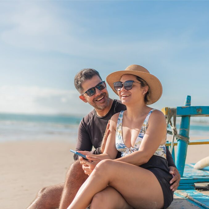 tourist couple using smartphone on the beach