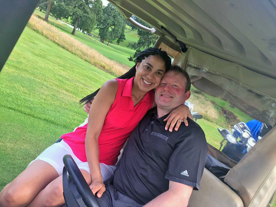 Guy and his wife sitting on a golf cart enjoying the sunshine and the game