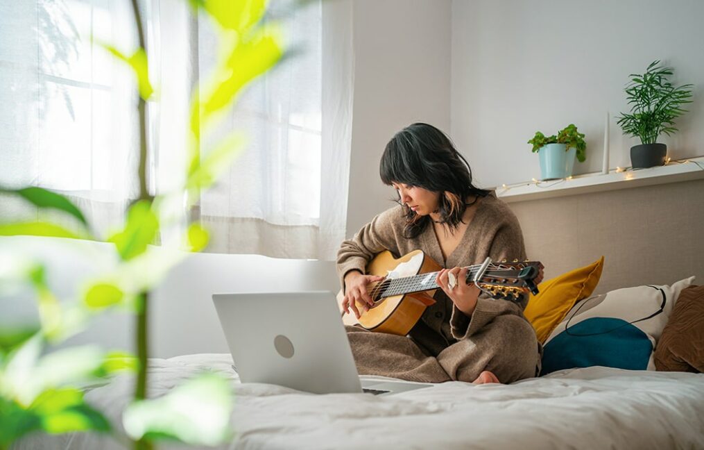 woman playing guitar on bed