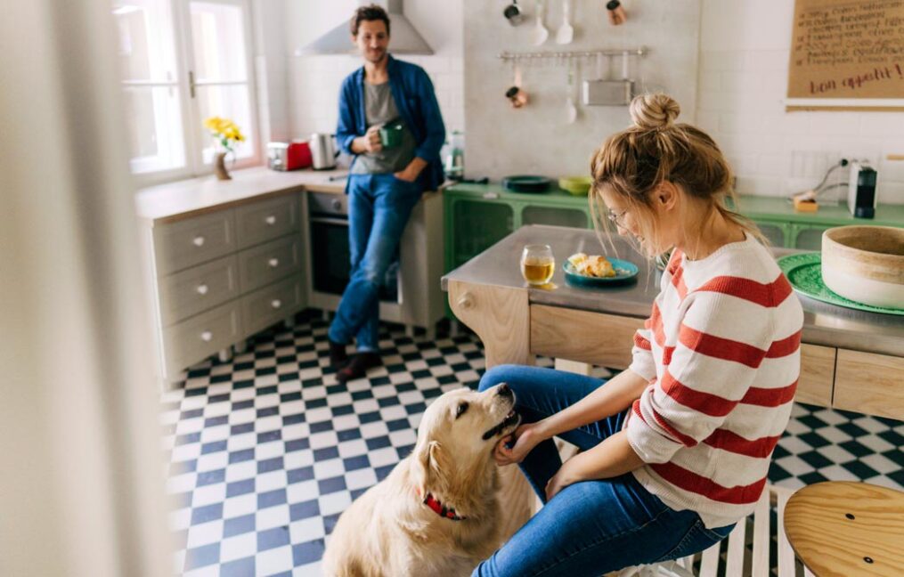 home refinancing-couple at home with their dog relaxing in the kitchen eating breakfast