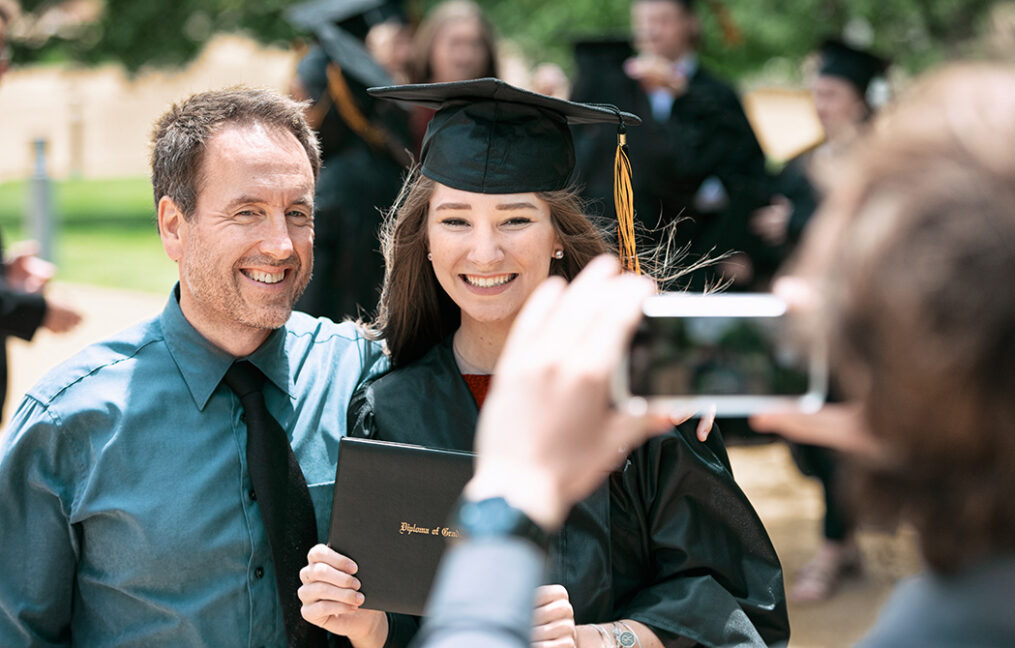 man and daughter posing for photo at graduation ceremony