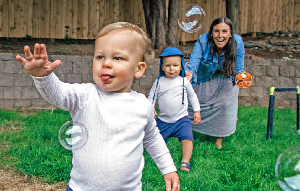 onpoint savers-twins playing with bubbles in the back yard with their mom