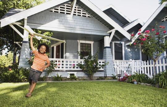 running child carrying glider in front yard