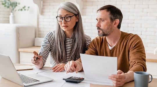 doing finances as a couple-woman with glasses-man with brown shirt