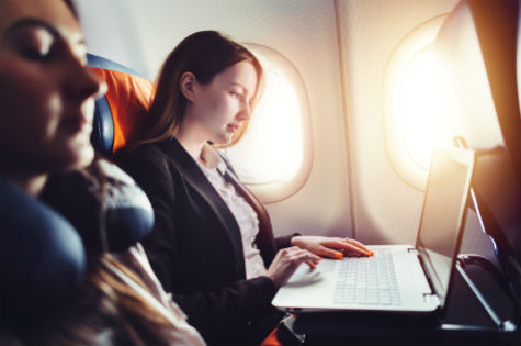 Woman sitting on a plane using her laptop.