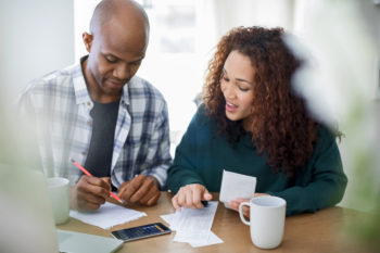 Couple calculating bills at table. Male and female are doing home finances. They are wearing casuals.