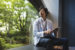 man sitting on a bench looking outside at green trees