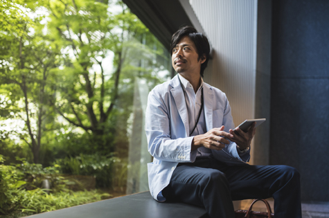man sitting on a bench looking outside at green trees