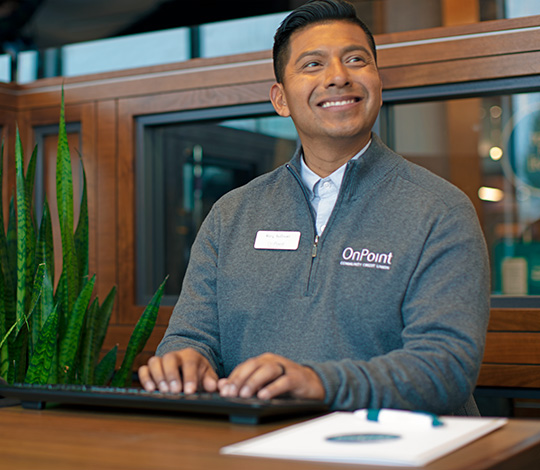 OnPoint member service representative sitting at their desk in local OnPoint branch ready to help member