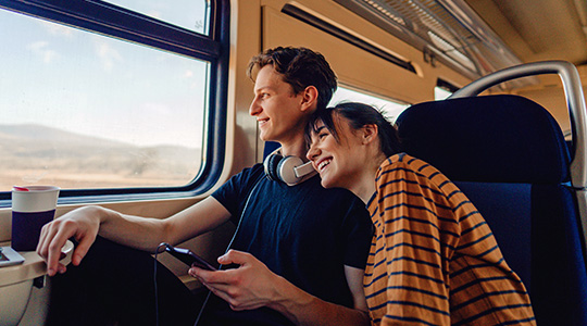 Young couple on a foreign train looking out the window