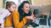 Young woman and her daughter sitting on the couch looking at her laptop