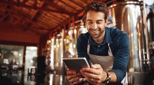 small business owner looking at a tablet at his brewery