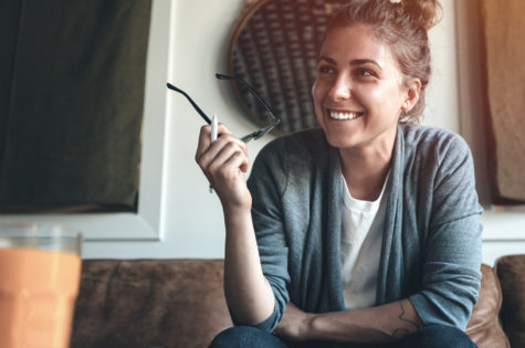 young woman holding her glasses and looking to someone off camera