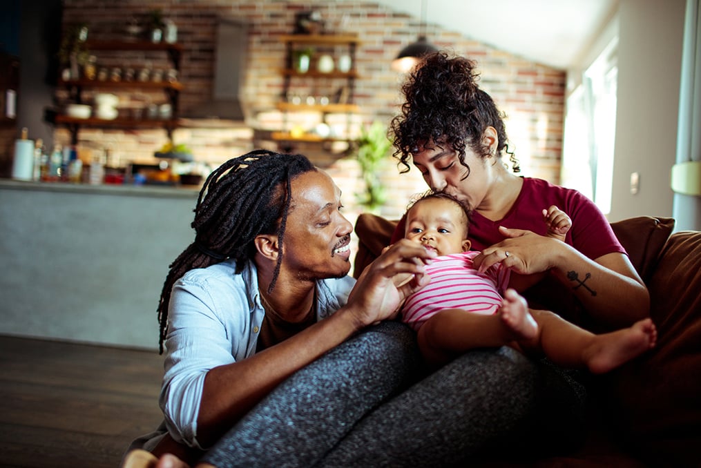 man-woman-and their young child sitting on the couch together as a family