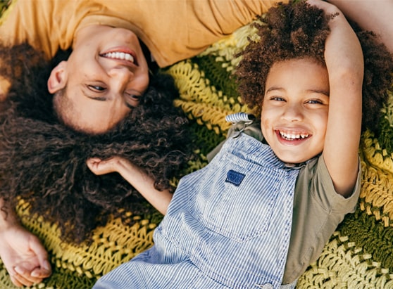 woman and her son laying on a blanket in the sunshine