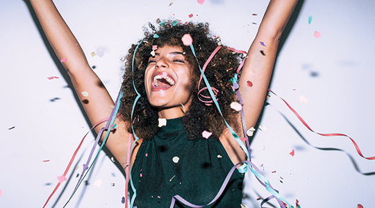 woman smiling with hands in the air and confetti