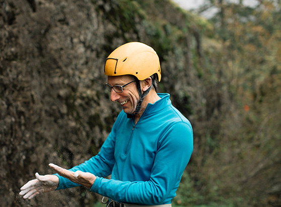 mature man with chalk on hands preparing to mountain climb