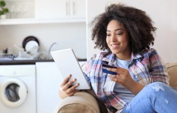 woman looking at credit card and digital device