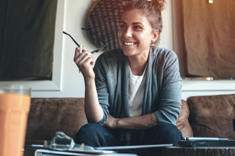 young woman sitting on her couch holding her glasses